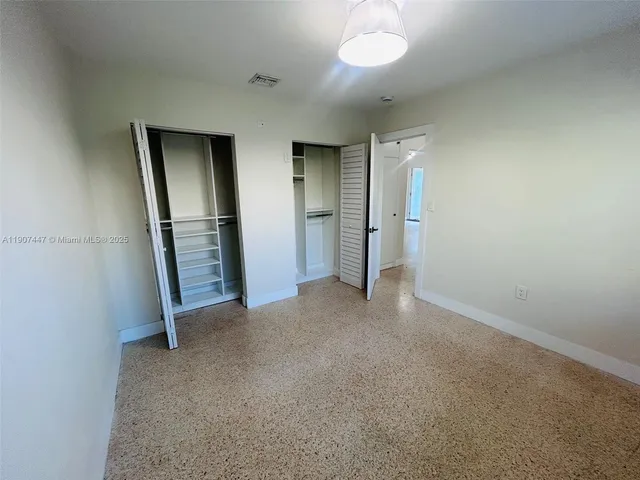 an empty room with closet and windows
