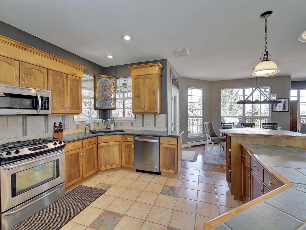 2332 North Falcon Point Court Grand Junction, CO 81507 - Photo 9 of 39 a kitchen with stainless steel appliances granite countertop a stove top oven a sink dishwasher a dining table and chairs with wooden floor