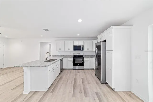 a large kitchen with a refrigerator a stove top oven a sink dishwasher and wooden floor