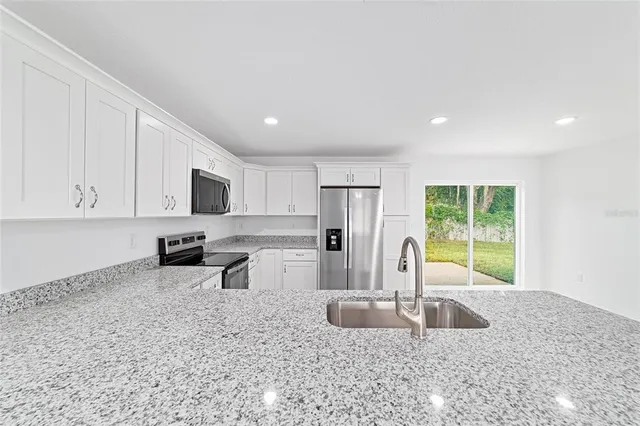 a kitchen with stainless steel appliances granite countertop a sink a stove and refrigerator
