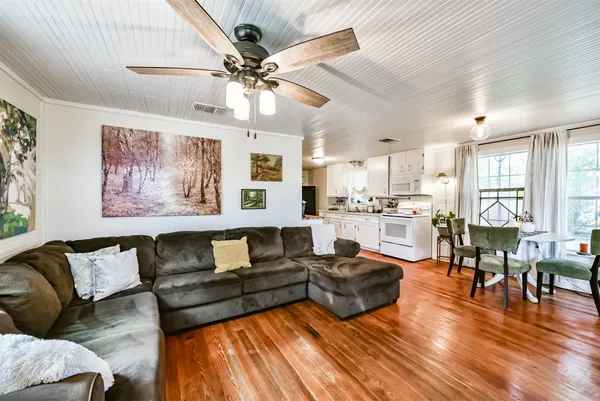 a living room with furniture kitchen view and a wooden floor