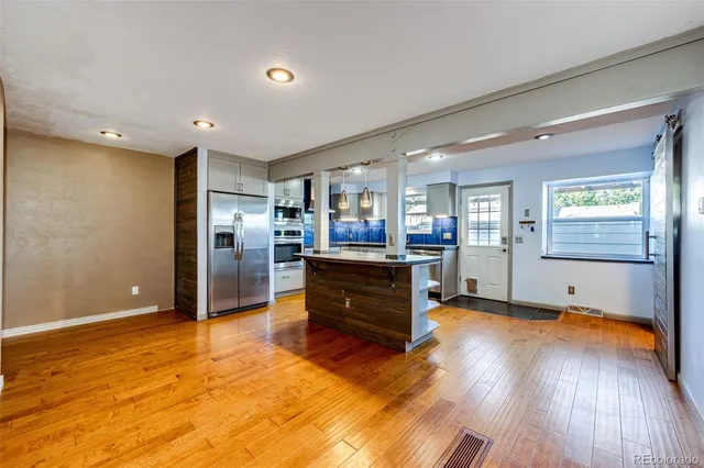 a kitchen with kitchen island granite countertop wooden floors and stainless steel appliances