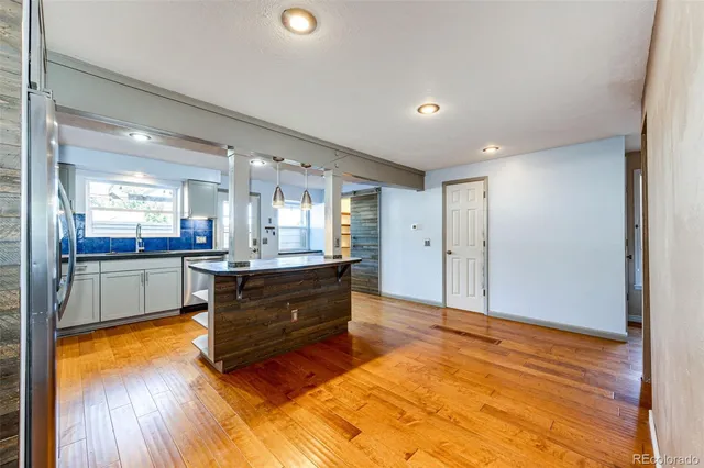 a living room with kitchen island granite countertop wooden floor and a sink