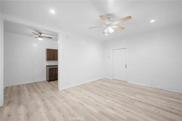 a view of an empty room with wooden floor and a ceiling fan