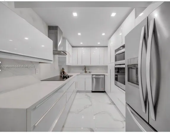 a large white kitchen with a sink stainless steel appliances and cabinets