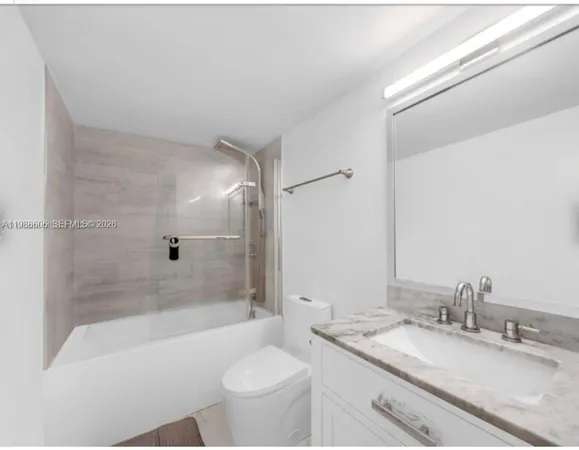 a bathroom with a granite countertop sink toilet mirror and bathtub