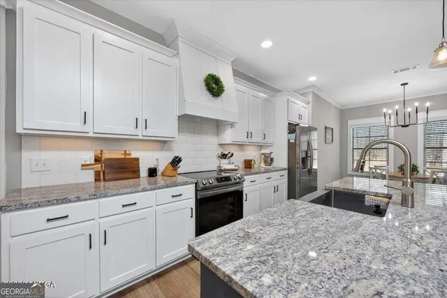 a kitchen with granite countertop white cabinets and stainless steel appliances