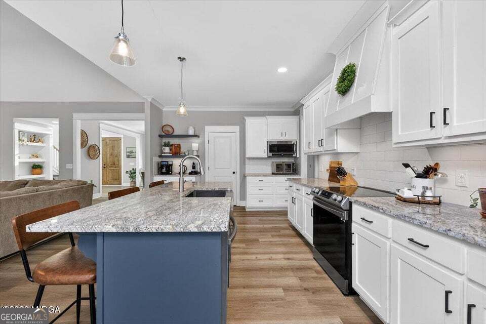 303 Tuxedo Circle Forsyth, GA 31029 - Photo 11 of 45 a kitchen with granite countertop kitchen island sink stove and white cabinets