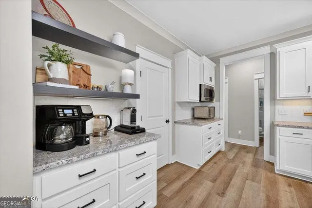 a kitchen with granite countertop white cabinets and stainless steel appliances