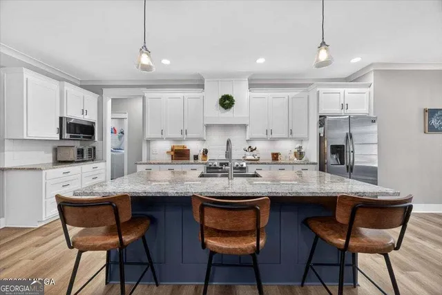 a kitchen with stainless steel appliances granite countertop a sink a stove a dining table and chairs