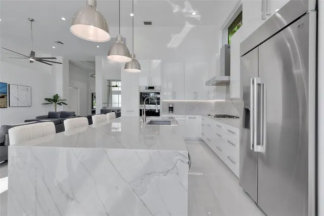 a large white kitchen with a refrigerator a sink and a large window