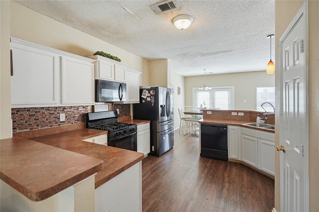 1934 Pin Oak Lane Lancaster, TX 75146 - Photo 8 of 27 a kitchen with a refrigerator a stove top oven a sink dishwasher and wooden cabinets with wooden floor