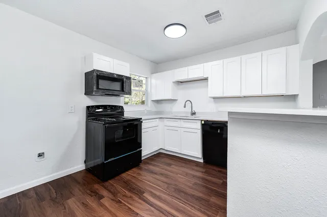 a kitchen with a sink a microwave and cabinets