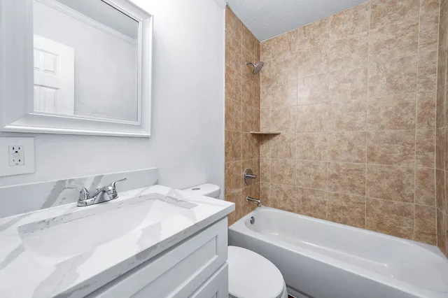 a bathroom with a granite countertop sink toilet and bathtub