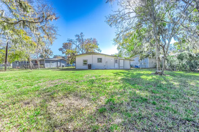 a view of a house with a big yard and large trees