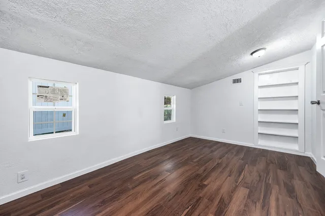 a view of an empty room with a window and wooden floor