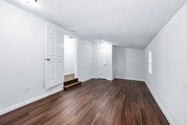 a view of an empty room with wooden floor