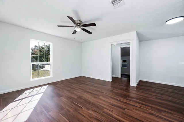 a view of an empty room with wooden floor and a window