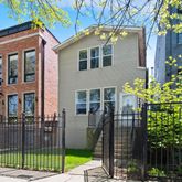 a view of a brick house with a small yard and a large tree