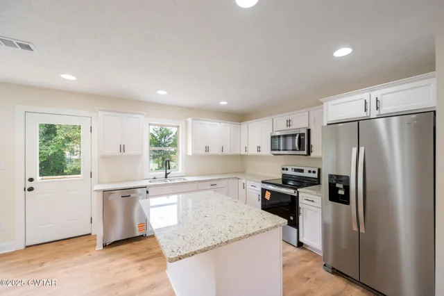 a kitchen with stainless steel appliances granite countertop a refrigerator a stove a sink and a refrigerator