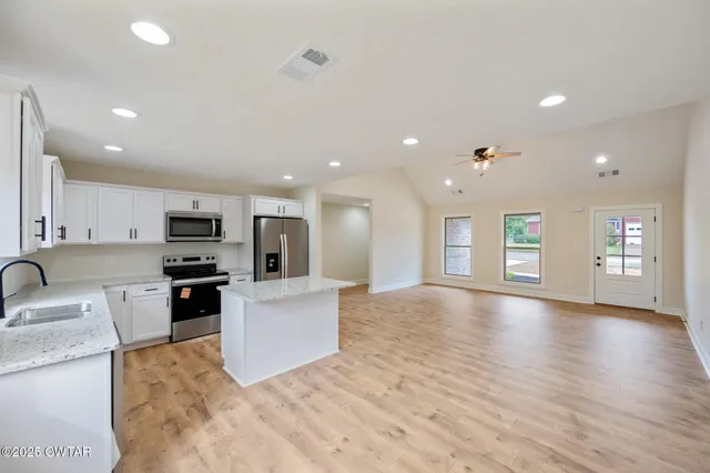 a view of kitchen with kitchen island wooden floor and refrigerator