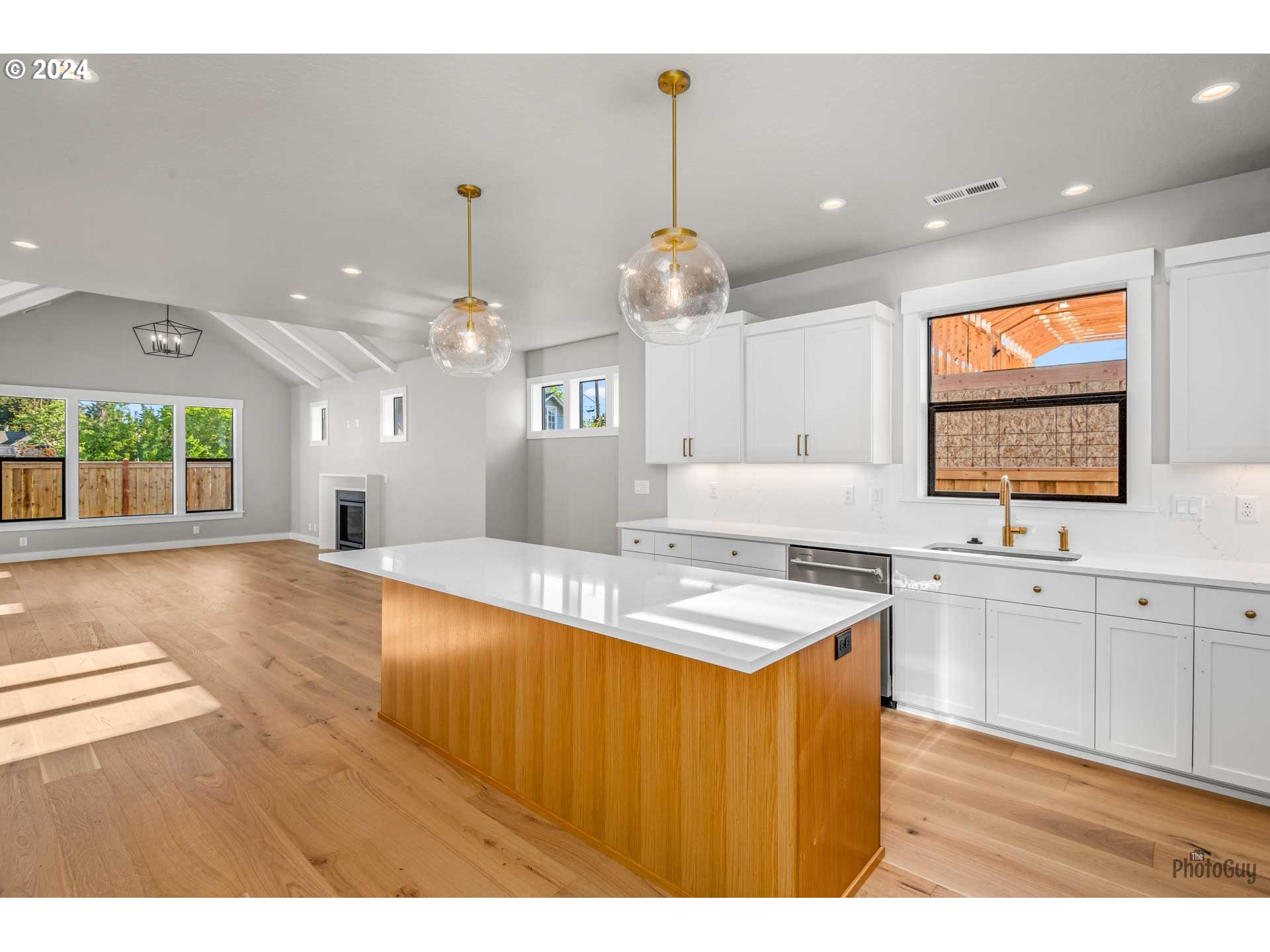32748 Coburg Road Eugene, OR 97408 - Photo 5 of 35 a large kitchen with kitchen island a stove a sink dishwasher and white cabinets with wooden floor