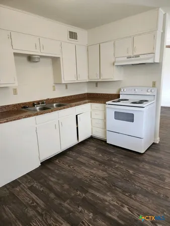 a kitchen with granite countertop white cabinets and white appliances