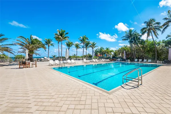 a view of a swimming pool with a lounge chair and palm trees
