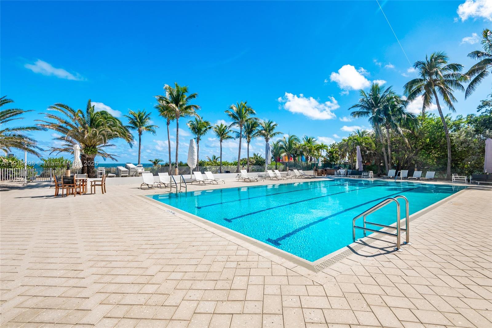 609 Ocean Drive, Unit 10H Key Biscayne, FL 33149 - Photo 2 of 21 a view of a swimming pool with a lounge chair and palm trees