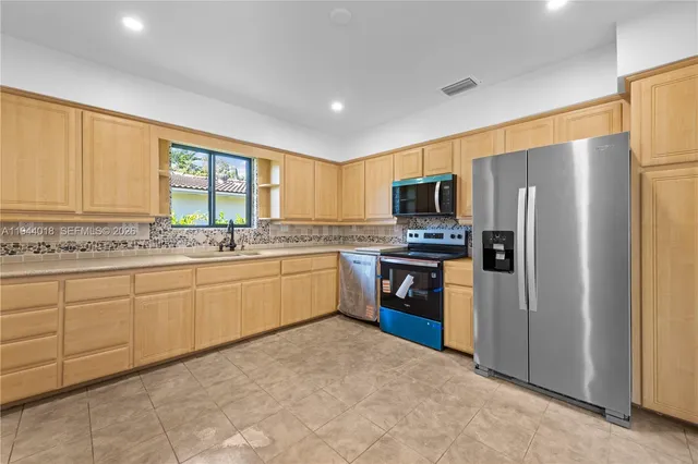 a kitchen with granite countertop stainless steel appliances a refrigerator sink and microwave