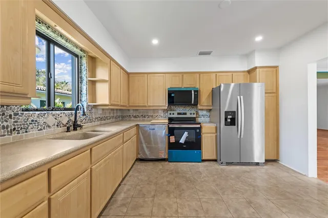 a kitchen with a sink a refrigerator and a stove top oven