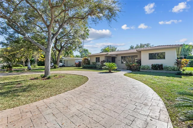 a front view of a house with a yard and trees