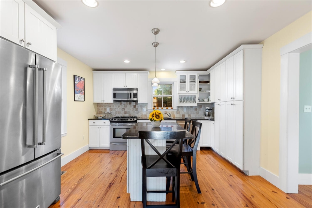 100 Willow Street Hamilton, MA 01982 - Photo 11 of 35 a kitchen with stainless steel appliances a refrigerator a stove a dining table and chairs with wooden floor