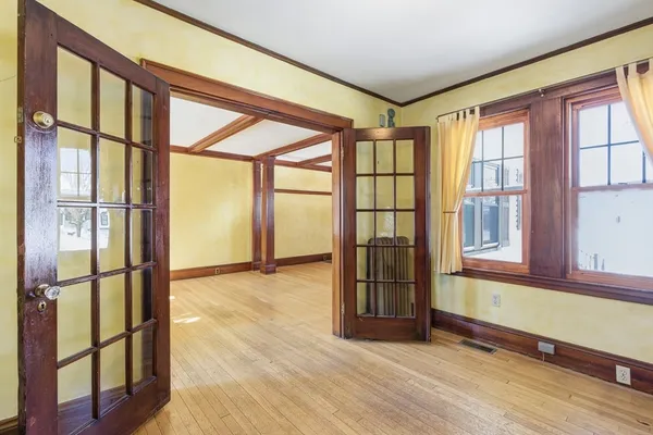 a view of an empty room with wooden floor and a window