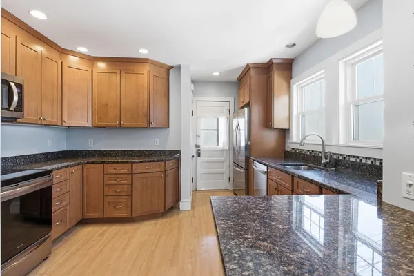 a kitchen with stainless steel appliances granite countertop a stove a sink and a refrigerator