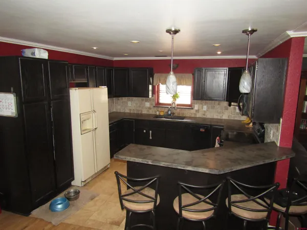 a kitchen with a table chairs refrigerator and wooden floor