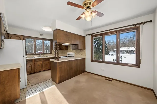 a large kitchen with a large window a sink stainless steel appliances and cabinets