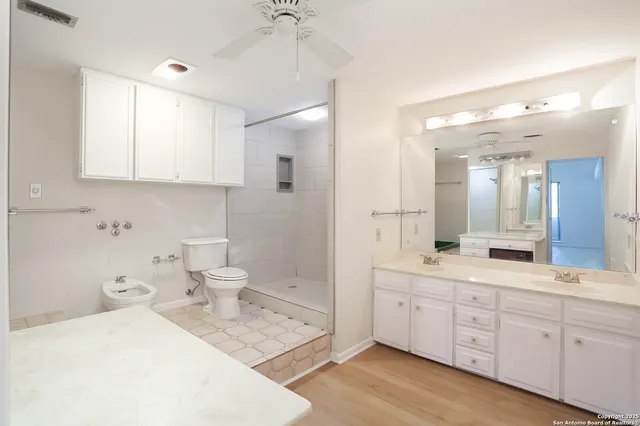 a spacious bathroom with a double vanity sink toilet mirror and bathtub