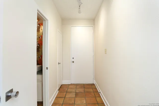 a view of a hallway with wooden floor and a bathroom