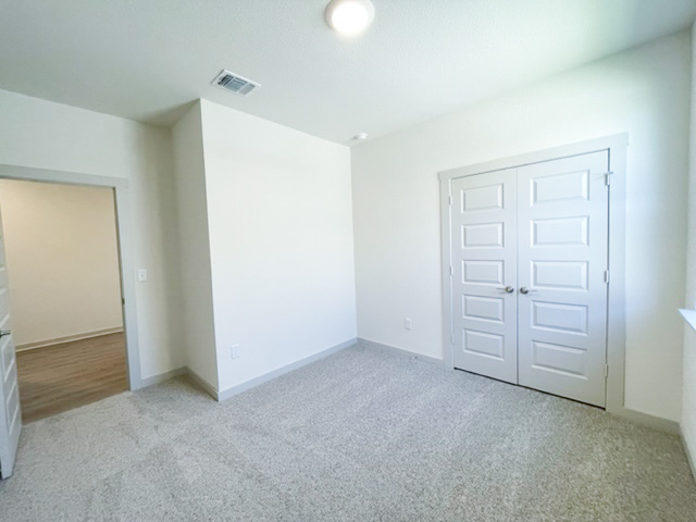 10616 Defender Trail Austin, TX 78754 - Photo 13 of 25 Unfurnished bedroom with light carpet and a closet
