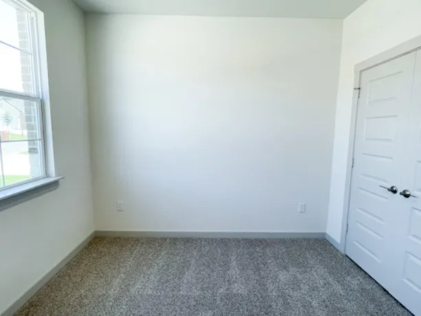 a view of an empty room with wooden floor and a ceiling fan