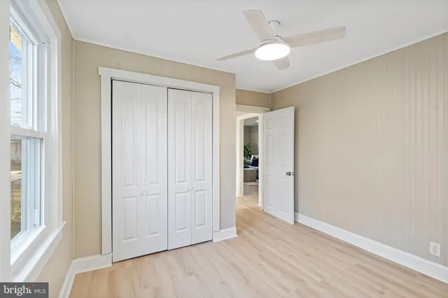 a view of empty room with wooden floor and fan