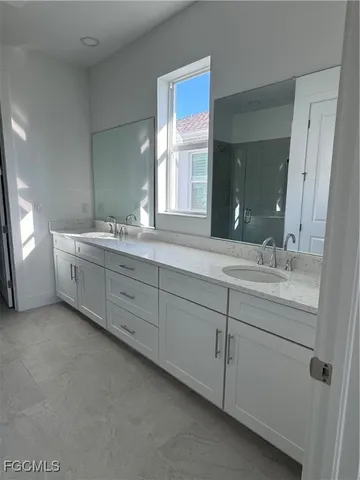 a spacious bathroom with double sink and mirror