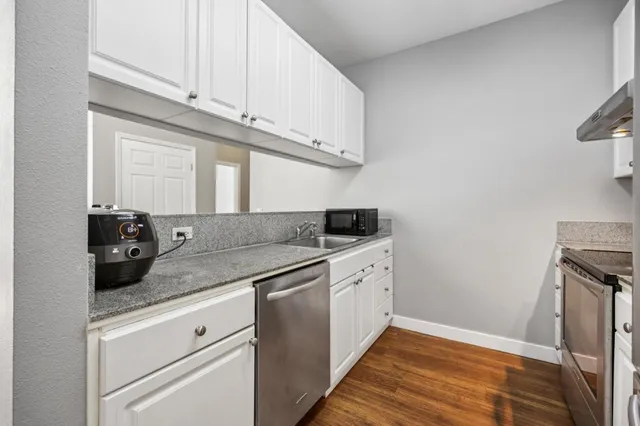a kitchen with granite countertop white cabinets and white appliances