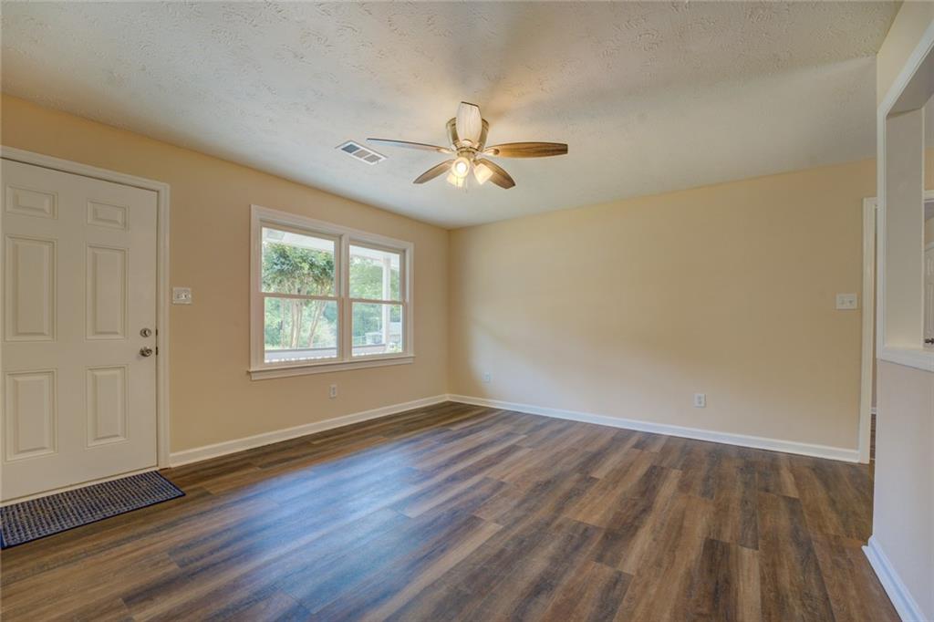 170 Hidden Pines Drive Covington, GA 30016 - Photo 3 of 22 an empty room with wooden floor ceiling fan and windows