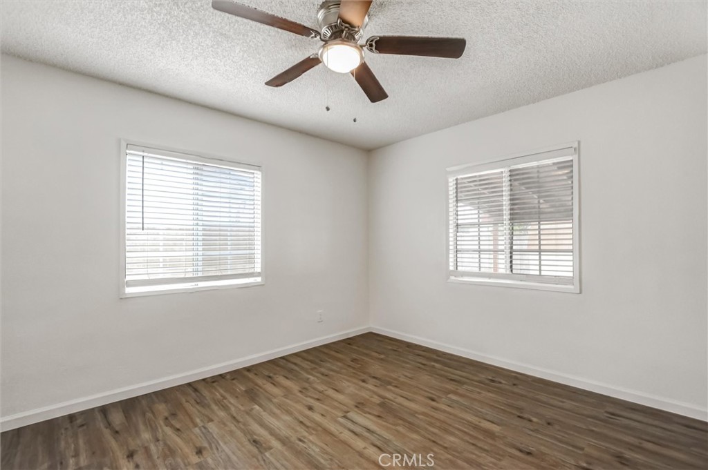 2734 Serrano Road North San Bernardino, CA 92405 - Photo 11 of 25 a view of an empty room with wooden floor and a window