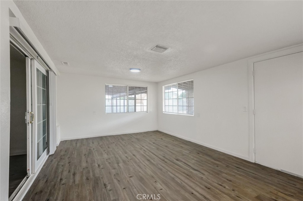 2734 Serrano Road North San Bernardino, CA 92405 - Photo 16 of 25 a view of an empty room with wooden floor and a window