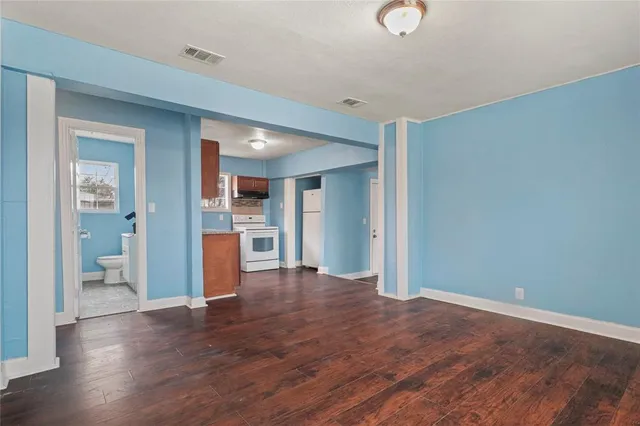 a view of a hallway with wooden floor and a kitchen