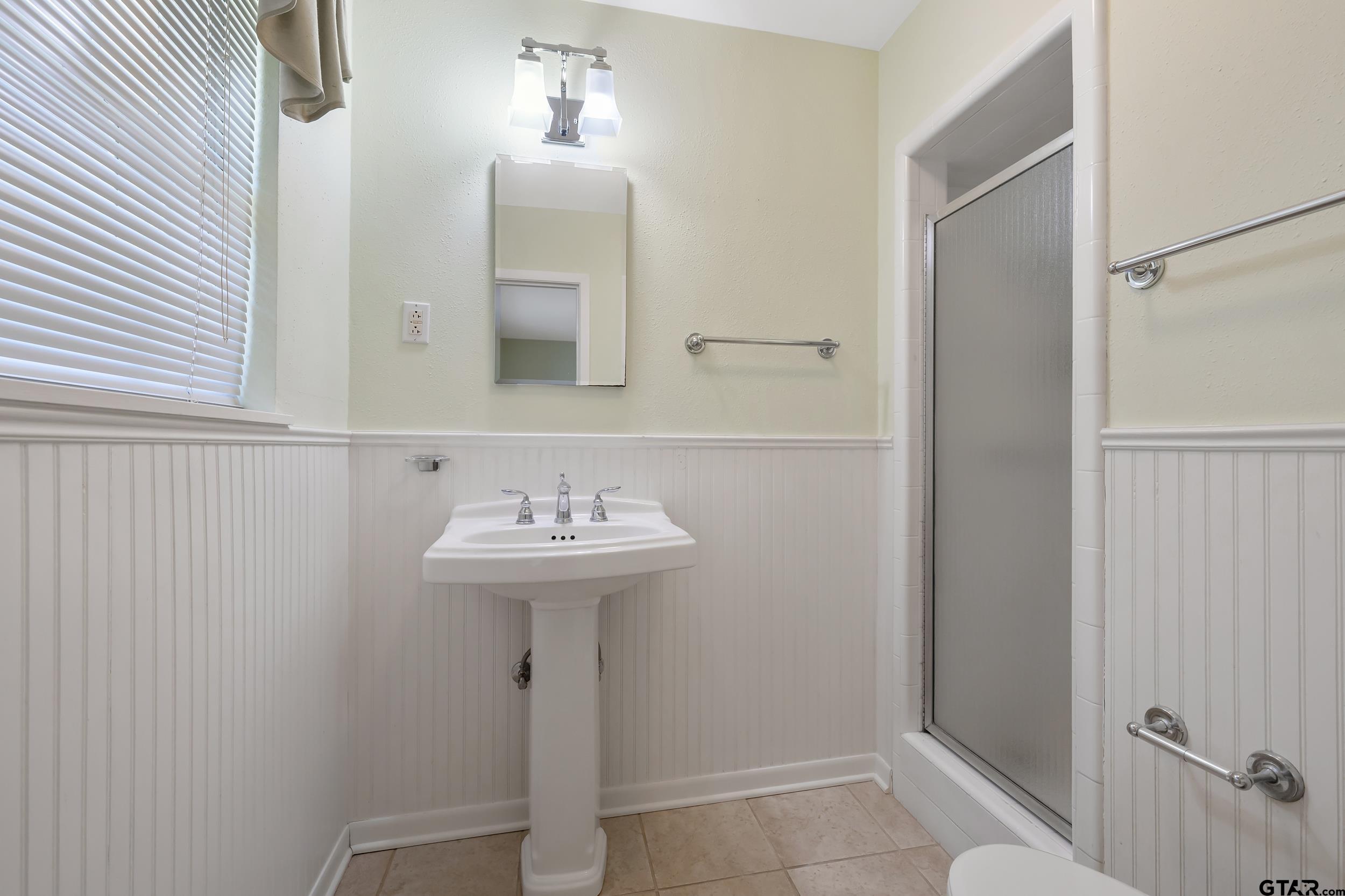 2026 Neeley Street Tyler, TX 75701 - Photo 21 of 26 a bathroom with a sink a mirror and shower