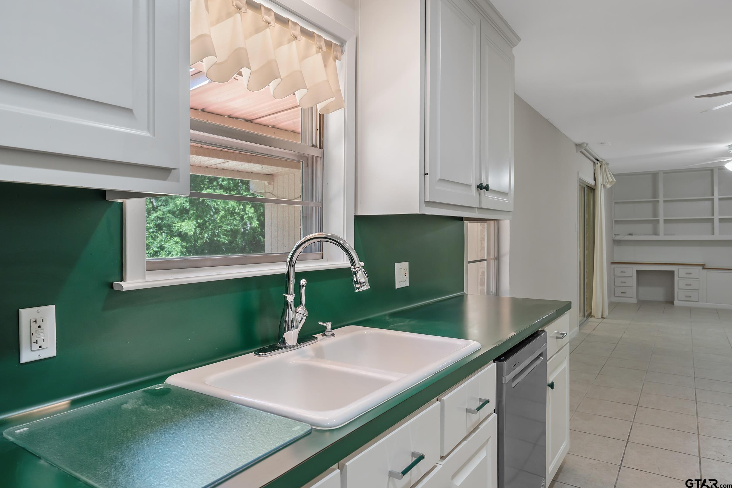 2026 Neeley Street Tyler, TX 75701 - Photo 8 of 26 a kitchen with green cabinets a sink and a window